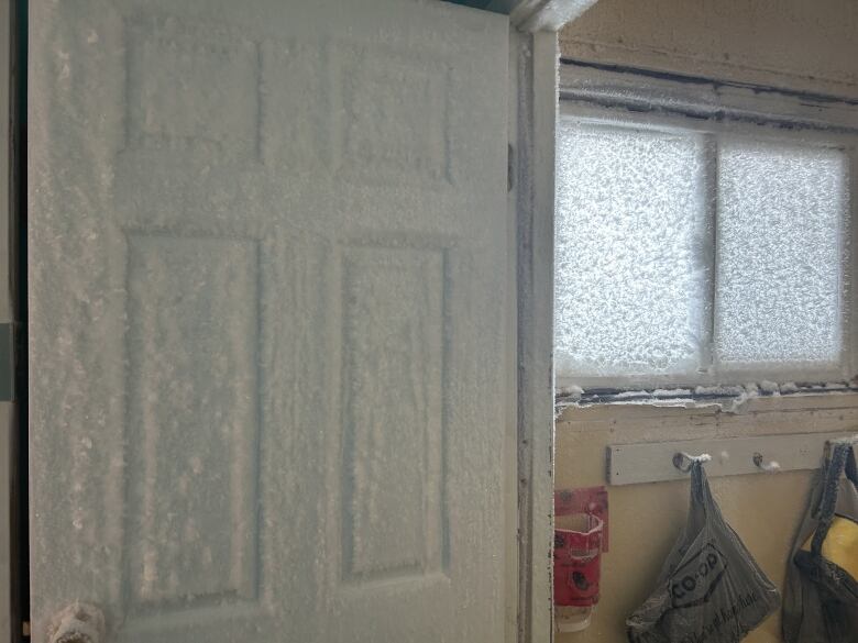 An open door covered in frost with frost covered windows beside it. 