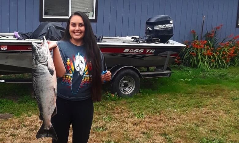 A woman with long dark hair holds a large fish