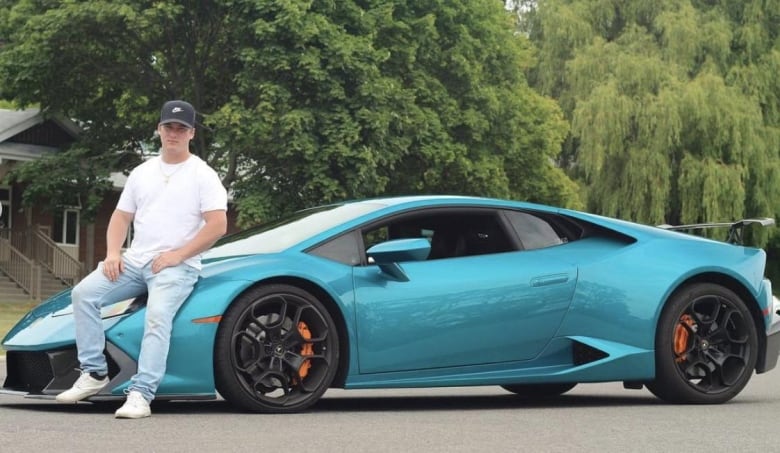 Man sits on a Lamborghini luxury car.