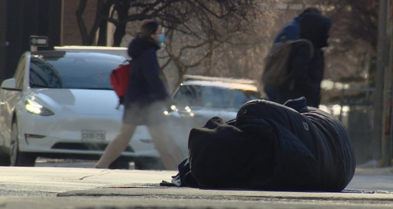 A person is seen sleeping on the street in downtown Toronto on Feb. 3, 2023 amid an extreme cold warning that sent the city into a deep freeze.