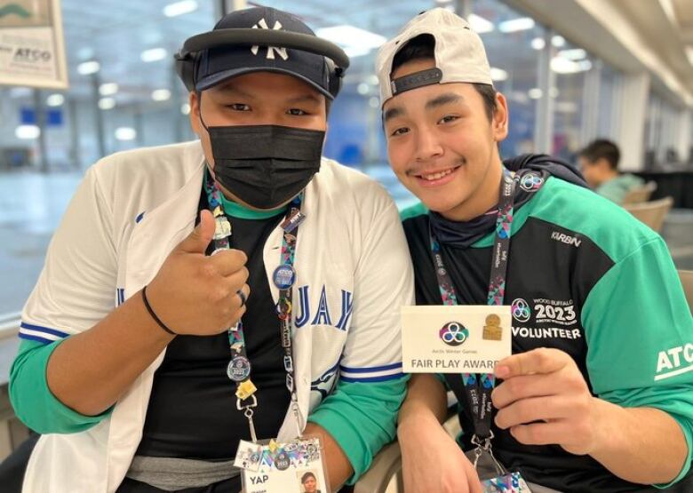 Two boys, one holding up a piece of paper.