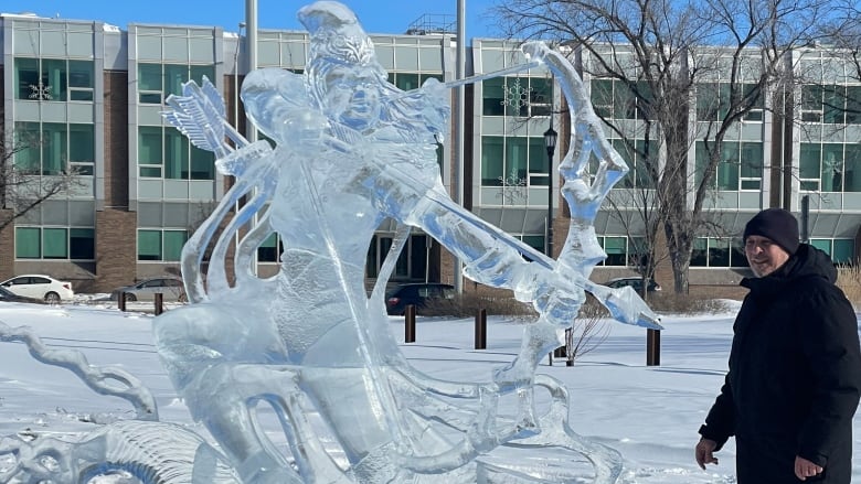 A man stands in front of an ice sculpture of an archer.