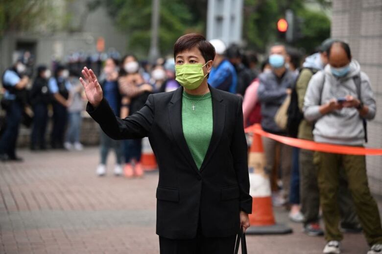 A woman in a black suit and a green top enters a court building in Hong Kong.