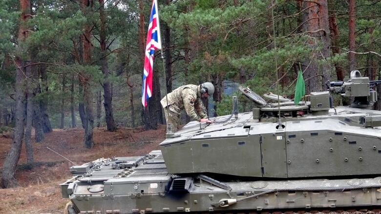 A British soldier checks equipment on a tank during a break in a NATO exercise at Camp Adazi near Riga, Latvia on Thursday, Nov.17, 2022.