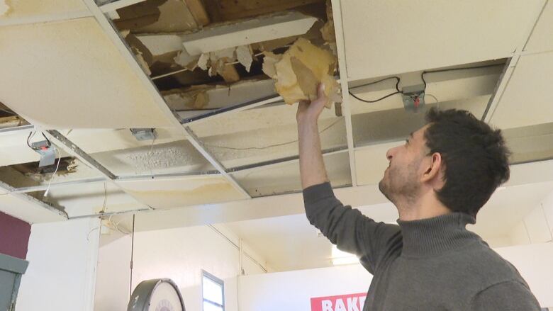 person taking tile from ceiling 