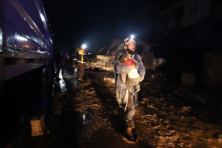 A rescuer carries a child rescued from rubble.