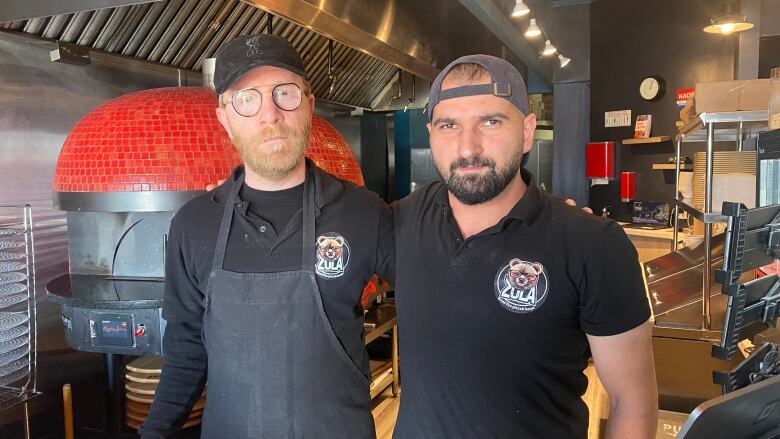 Two workers at a take-out joint pose for a photo together.