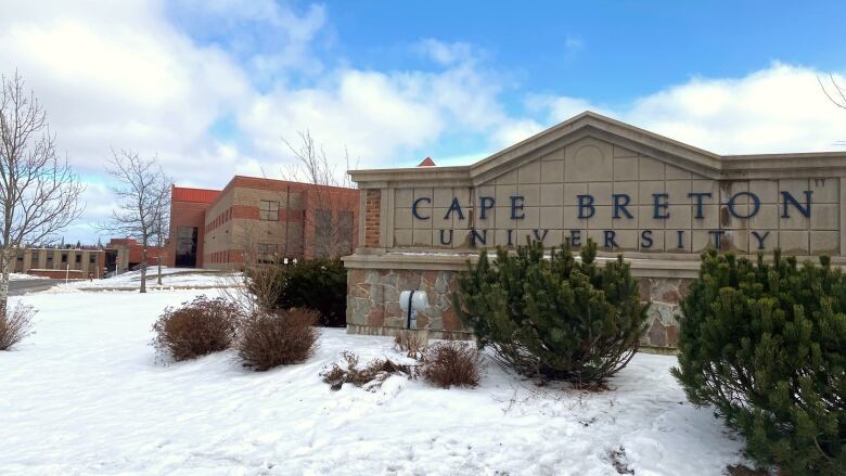 A sign saying Cape Breton University sits in front of a brick building.