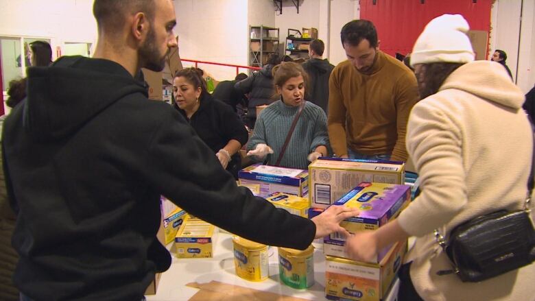 Volunteers stand around a table piled with donations of baby supplies.