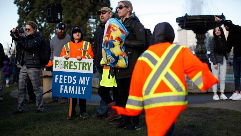 Forest industry workers and their supporters stand shoulder-to-shoulder with picket signs.