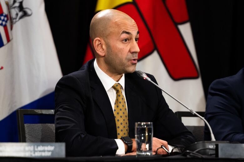 Shiny man in suit at microphone.