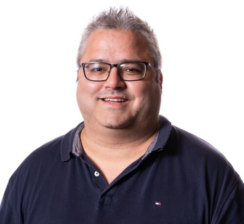 A professional photo of a man with glasses in a polo shirt.