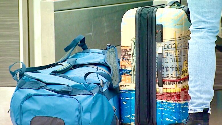 A suitcase and backpack are on the floor at an airport check-in counter.