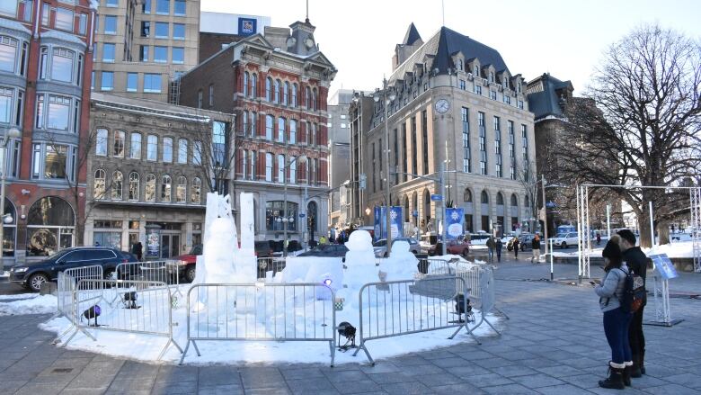 Pedestrians stop to look at ice carvings in Confederation Square in Ottawa.