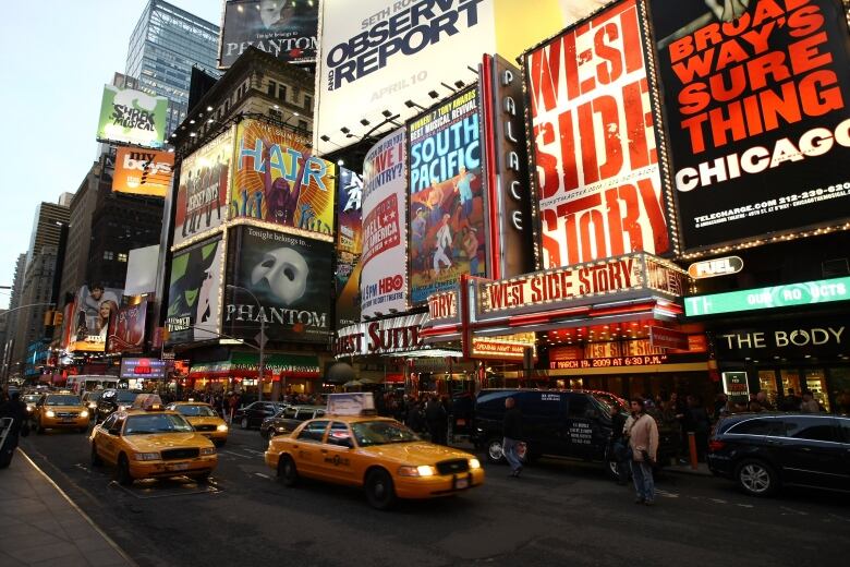 A street with yellow taxi cabs and billboards with lights.