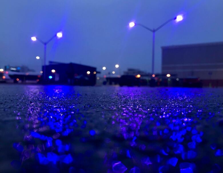 blue and purple light glitters over rainy pavement