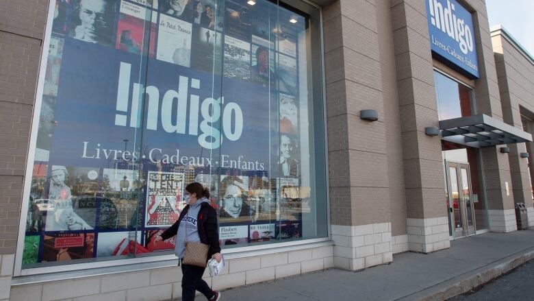 A woman walks past the display window of an Indigo book store.