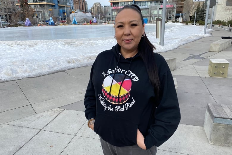 A woman in a Sobercrew sweatshirt stands by a Calgary apartment building.