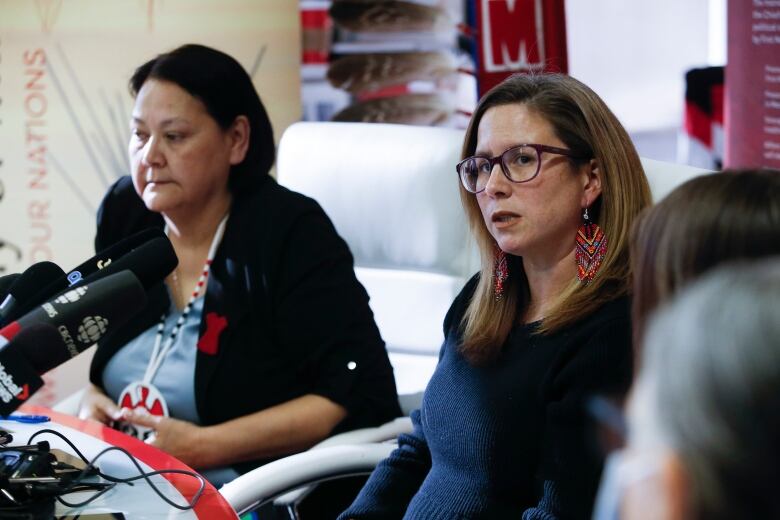 A woman speaks as another listens next to her.