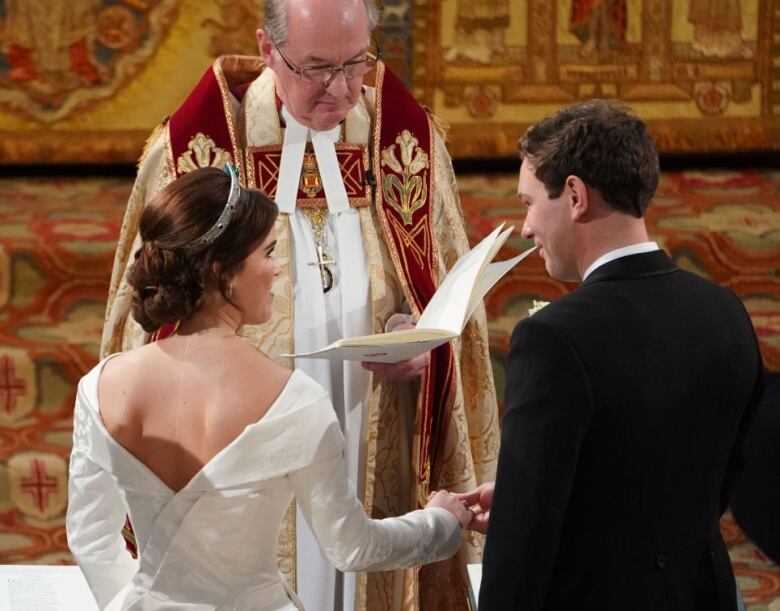 A couple holds hands as they stand at the altar during their wedding ceremony.