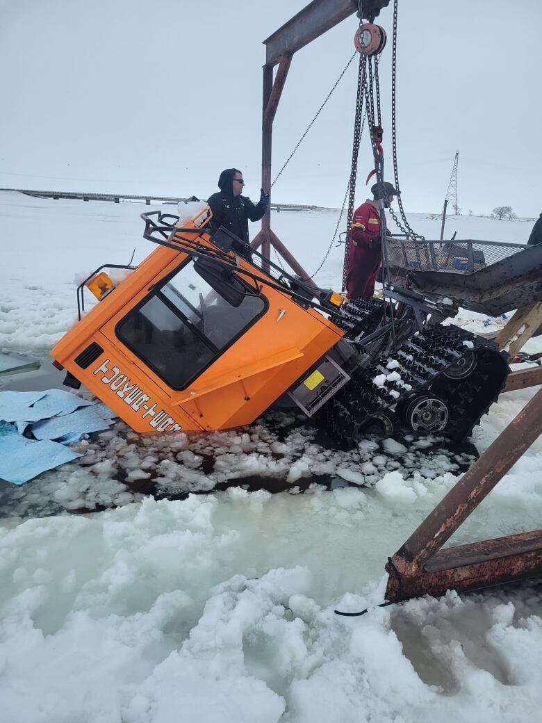 A giant machine sits half emerged in water surrounded by ice.