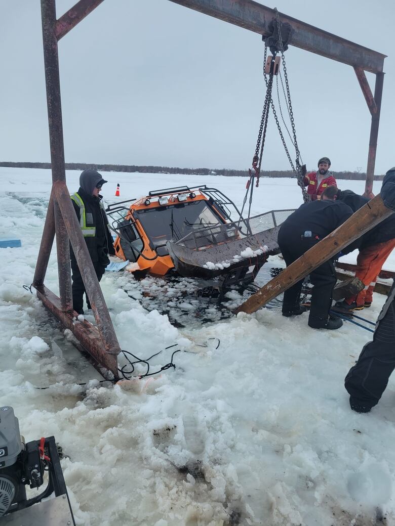 A giant machine sits half emerged in water surrounded by ice.