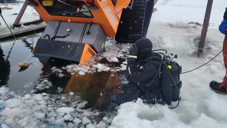 A giant machine sits half emerged in water surrounded by ice with a scuba diver ready to dive in beside it.