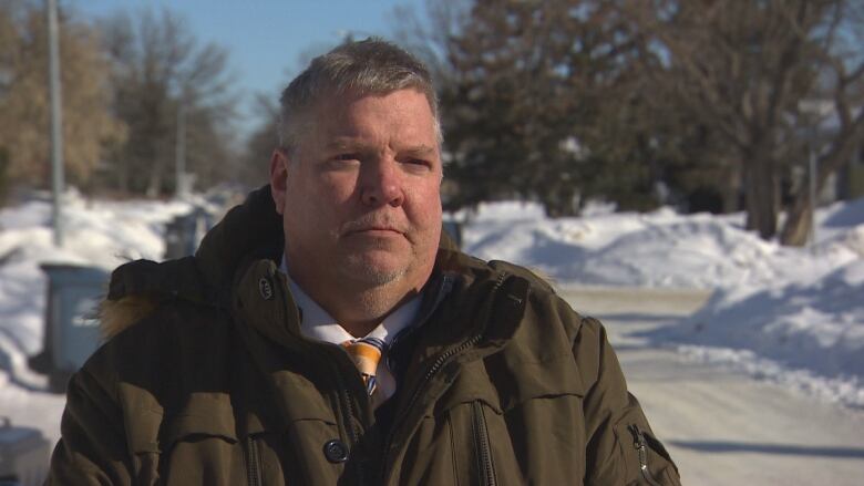 A man in a winter jacket stands outside.