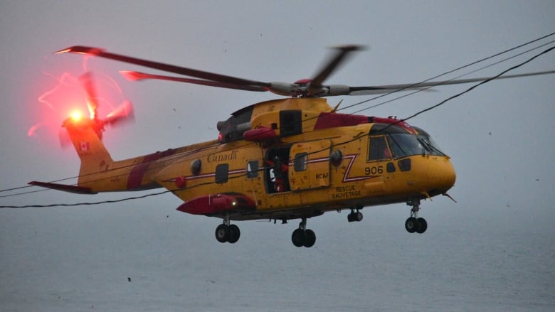 A yellow cormorant helicopter in flight.