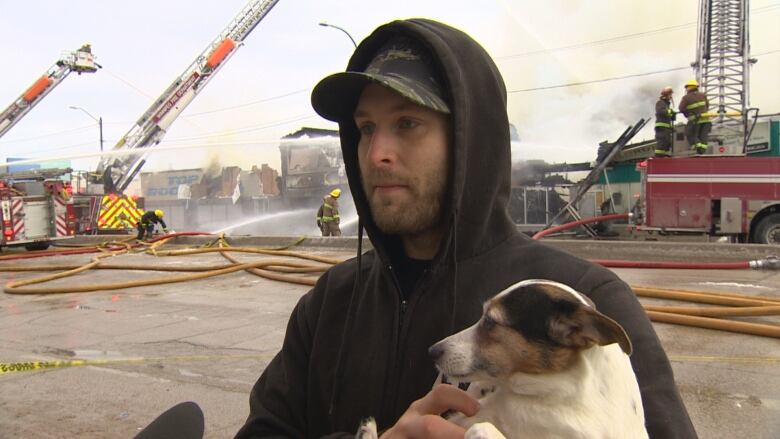 A man holds his dog near the scene of a fire in Winnipeg.