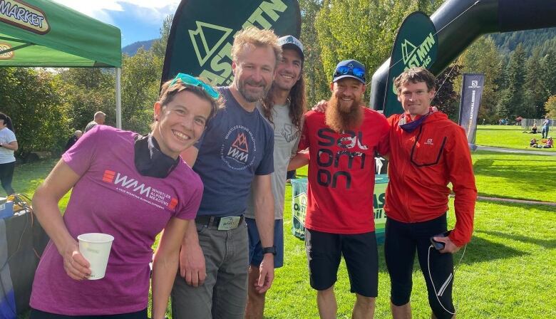 A group of five ultra marathon runners, race organizers and volunteers smile for a picture.