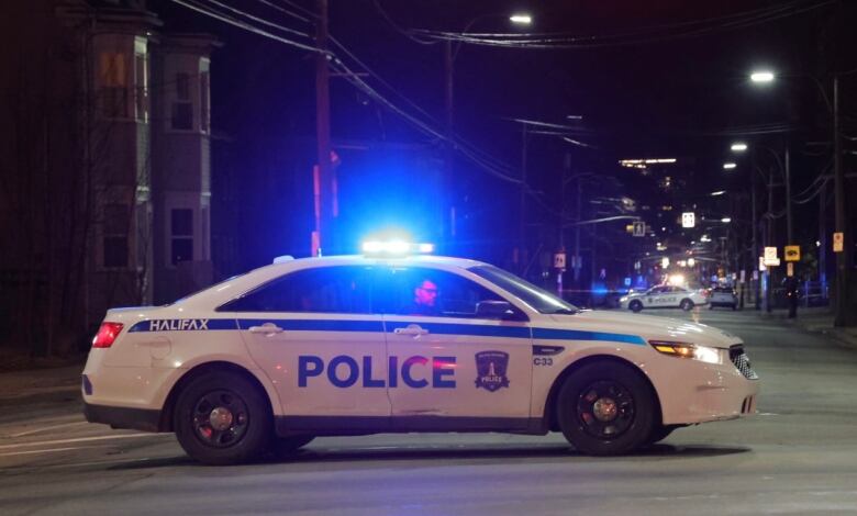 A Halifax police car is parked in the middle of the street and another police car can be seen in the distance also parked in the middle of the street.