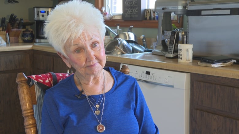 A woman sits in her kitchen.