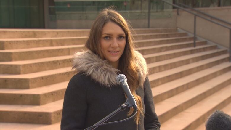 A woman stands on the steps of a court house.