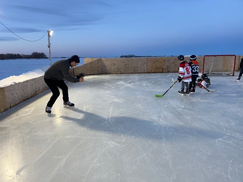 A filmmaker, left, captures video of children on a rink.