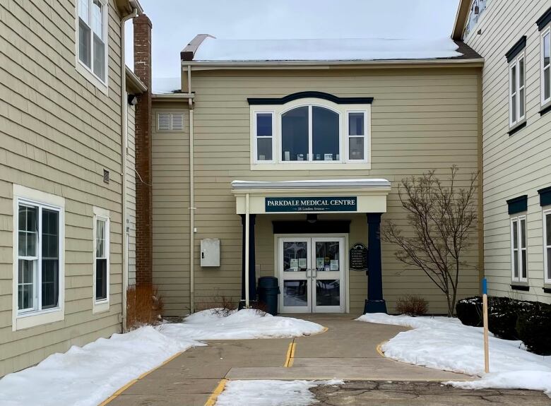 The exterior of a beige office building with a pavement courtyard in front, with snow on the ground. 