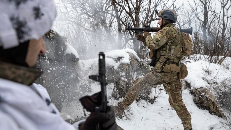 A soldier points a weapon at a frontline position.