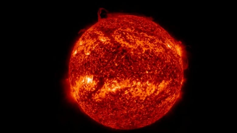 A satellite image of the sun shows a large plume of gas rising in the northern polar region of the sun.