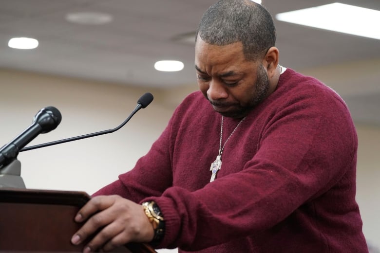 An emotional man stands at a lectern