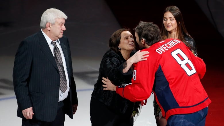 A hockey player kisses his mother during a ceremony at centre ice.