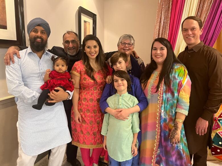 A smiling multiracial family dressed in Indian clothes. 