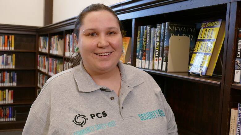 A woman is wearing a grey polo shirt with the letters 