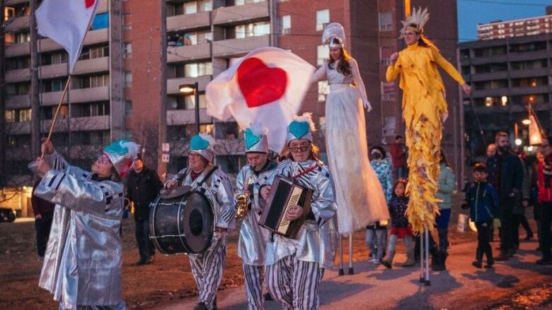 A parade walks through the streets at night.