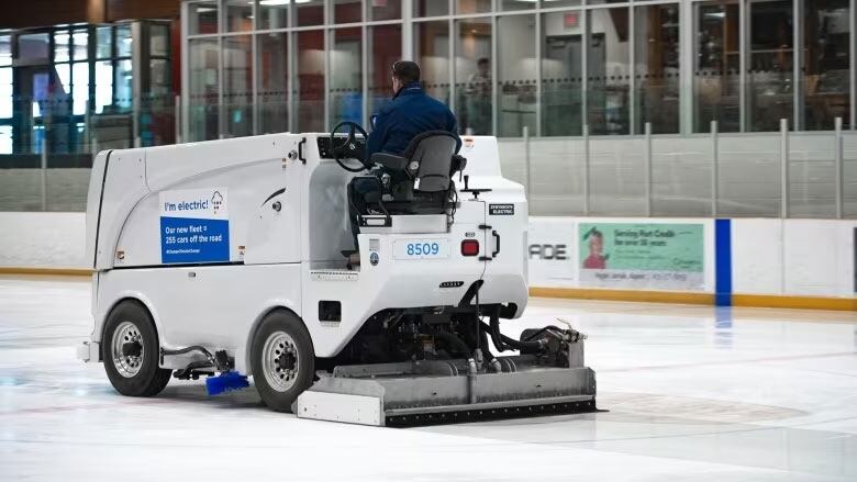 An electric ice resurfacer does its thing in an arena.