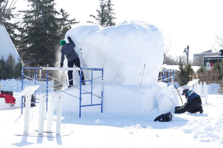 A person works on a snow sculpture.