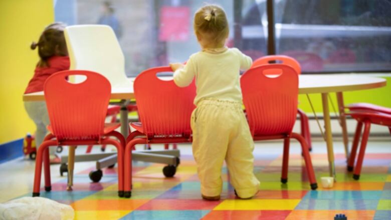 Toddlers seen from behind around a tiny table.