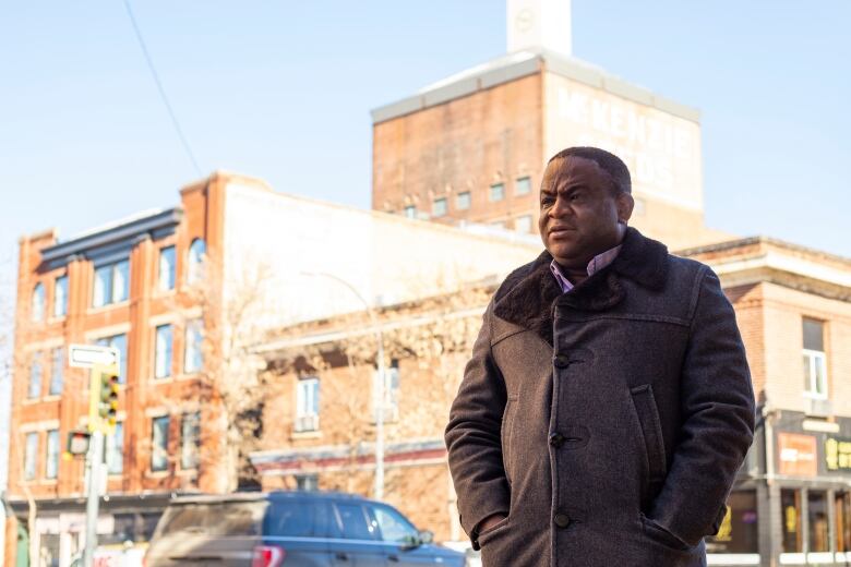 A man stands in a fancy winter jacket outside heritage buildings.