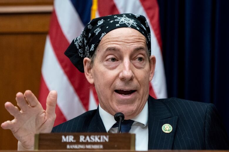 A closeup of a man on a panel wearing a suit and a bandana is shown.