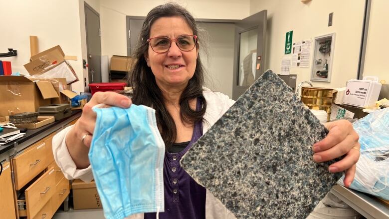 Denise Stilling, a mechanical engineer at the University of Regina, holds up a used face mask and a square tile made of different colours.