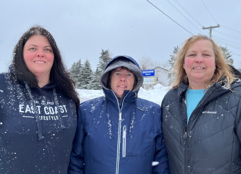 Three women stand next to each other and smile for the camera.